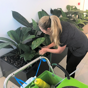 Showing a service person in black uniform watering plants.